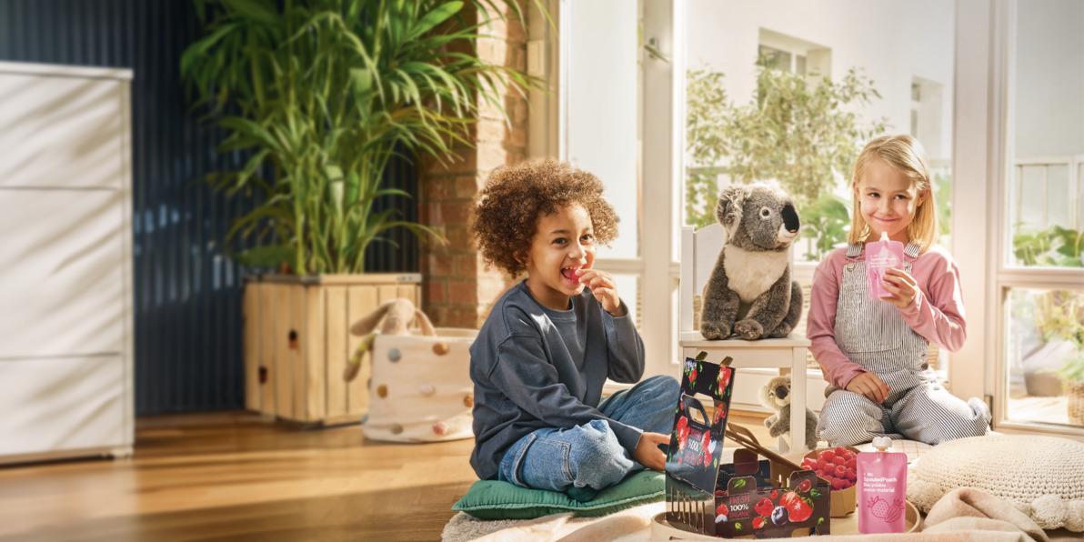 Chłopiec i dziewczynka siedzący w salonie na dywanie, otoczeni opakowaniami na żywność firmy Mondi.