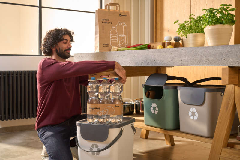 Mężczyzna otwierający sześciopak butelek wody PET zapakowanych w opakowanie Mondi Hug&Hold.