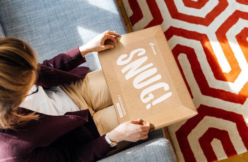 A woman holding an EnvelopeMailer from Mondi with the writing "Snug".